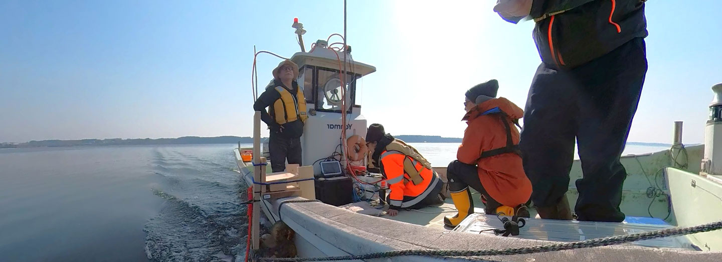 Archaeologists on a boat surveying Lake Ogawara, Japan