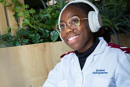 A person in student radiographer uniform, smiling.
