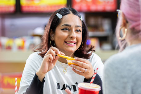 Two students sitting in a fast food restaurant, chatting and eating.