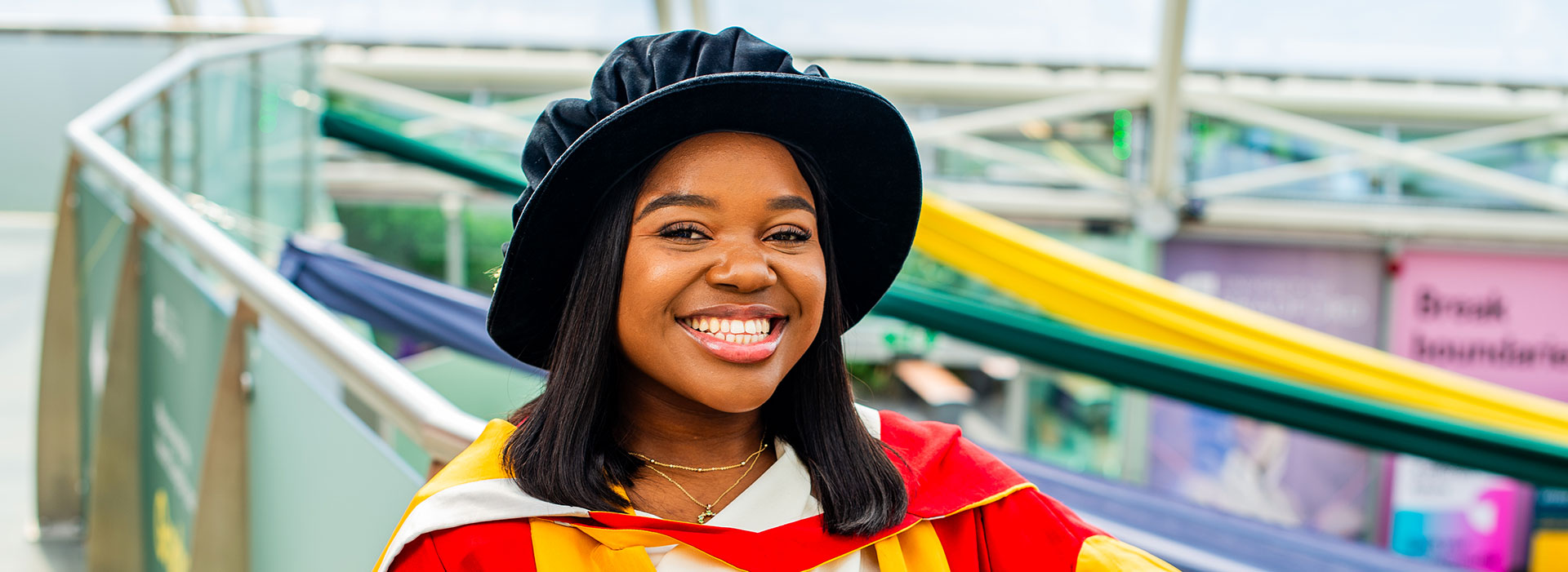 Vee Kativhu, Doctor of the University (2024) posing in a gown at ceremonies